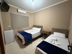 a hotel room with two beds and a tv at Point Hotel in Tanabi