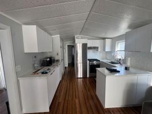 a white kitchen with white cabinets and wooden floors at Sherkston Shores Cottage in Port Colborne