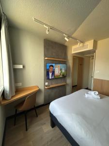 a room with a bed and a tv on a wall at Hôtel Inn Design Montluçon in Montluçon