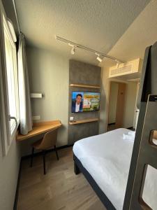 a room with a bed and a desk and a tv at Hôtel Inn Design Montluçon in Montluçon +30 photos