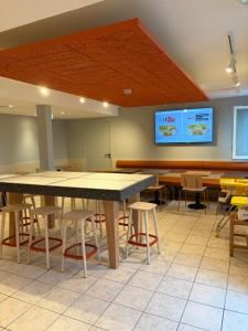 a large room with tables and chairs and a screen at Hôtel Inn Design Montluçon in Montluçon