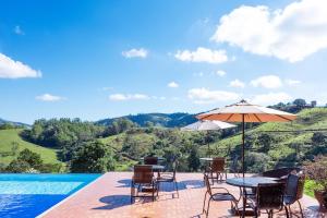a pool with chairs and tables and an umbrella at Pousada Estância das Montanhas Boutique in Águas de Lindoia +46 photos