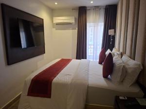 a hotel room with a bed with a television on the wall at Danville Hotel Ltd in Freetown