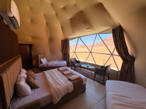 a hotel room with two beds and a large window at Rum Red Sand Luxury Camp & Jeep Tours in Wadi Rum