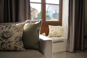 a couch with pillows sitting in front of a window at Kalan Boutique Stay in Žirovnica