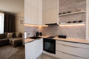 a kitchen with white cabinets and a living room at Kalan Boutique Stay in Žirovnica