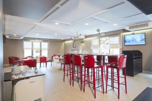 un restaurant avec des chaises rouges et un bar dans une chambre dans l'établissement Campanile Caen Est - Mondeville, à Mondeville