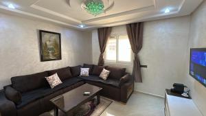 a living room with a couch and a tv at Appartement Agadir Tilila 1 pour couples mariés et familles in Agadir
