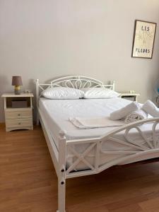 a white bed in a white bedroom with a night stand at Alex Apartment in Pogradec
