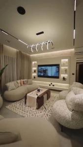 a living room with a tv and a couch and chairs at مدينتي برافادو in Madinaty