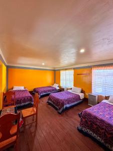 a room with four beds and a table and chairs at Hospedaje Vista Ausangate in Labramarca