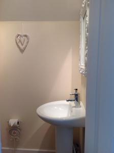 a bathroom with a white sink and a heart on the wall at Fring House Bed and Breakfast in Seaton +34 photos