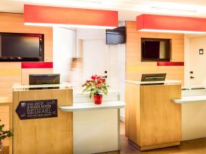 a restaurant with a counter with a potted plant at ibis Porto Centro São Bento in Porto