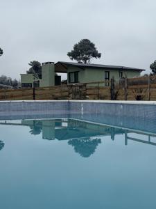 a pool of water in front of a house at Crisálida Cabañas Villa Yacanto in Villa Yacanto