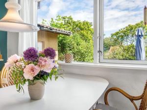 a vase of flowers sitting on a table in front of a window at 4 person holiday home in Allinge in Allinge