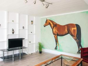 a painting of a horse on the wall of a living room at Charming Retreat in Ringkobing in Ringkøbing +20 photos