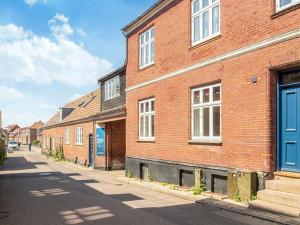 a brick building with blue doors on a street at Charming Retreat in Ringkobing in Ringkøbing