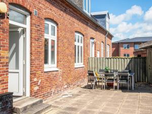 a patio with a table and chairs next to a brick building at Charming Retreat in Ringkobing in Ringkøbing +41 photos