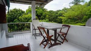 a balcony with a table and chairs and trees at Pousada e Chocolateria Muito Mais in Itaparica