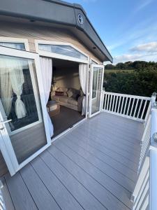 a mobile home with a deck with a couch at Sandytoes and Seaside smiles in Wyke Regis