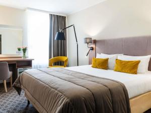 a hotel room with a large bed with yellow pillows at Mercure Lublin Centrum in Lublin