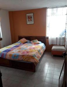 a bedroom with a bed with a colorful comforter and a window at Alojamiento Rosales in San Antonio