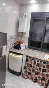 a kitchen with a counter with a microwave and a sink at مفروشة السعادة in Tlemcen