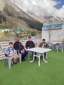 a group of people sitting around a table on the grass at Turgil Green Resort in Nomal