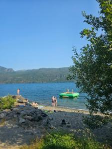 people on a beach with a green boat in the water at Sauda Fjord Camping in Saudasjøen