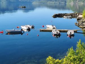 a group of boats docked at a dock on a lake at Sauda Fjord Camping in Saudasjøen