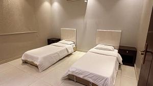 two beds in a hospital room with white sheets at شاليهات تولين in Taif