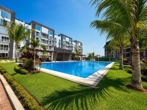 a swimming pool with a palm tree and some buildings at Nice AptPoolBeach ClubParkingGymACBarraVieja in Barra Vieja