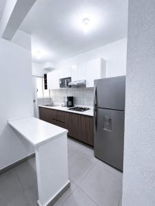 a kitchen with a refrigerator and a table in it at Nice AptPoolBeach ClubParkingGymACBarraVieja in Barra Vieja