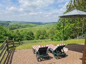 a patio with two chairs and an umbrella at Karawankenpanorama L in Liebenfels