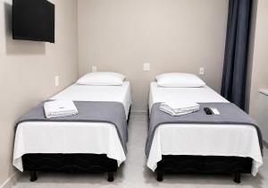 two twin beds in a room with a tv at Hotel Campina Center in Campina Grande