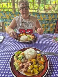 a man sitting at a table with a plate of food at Glowing Mountain view tree house in Loanengo +73 photos