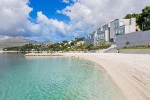 a beach with a building and the water at Apartments and rooms with parking space Trogir - 13102 in Trogir