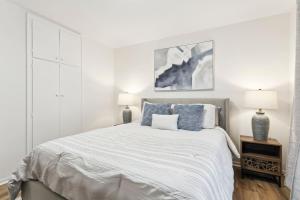 a white bedroom with a large bed and two lamps at Modern 3BR Home, Minutes to Lake & Port Credit in Mississauga