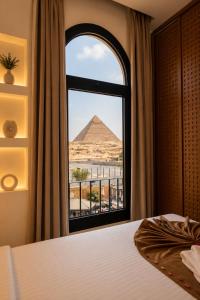 a bedroom with a view of the pyramids from a window at Le Pacha Pyramids Hotel in Cairo +30 photos