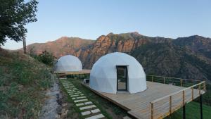 two domes on a wooden deck with mountains in the background at Glamping Yeghegis in Yeghegis +14 photos