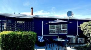 a blue house with a table and chairs and an umbrella at Gone Potty 1 in Alexandra