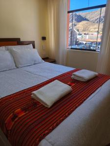 ein Bett mit zwei Handtüchern darauf und einem Fenster in der Unterkunft Hostal Yaravi in Chivay + 21 Fotos