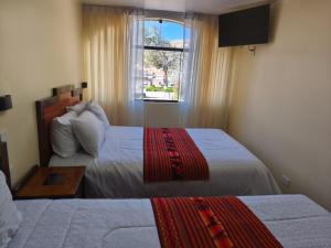 ein Hotelzimmer mit zwei Betten und einem Fenster in der Unterkunft Hostal Yaravi in Chivay