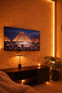 a tv on a wall with a picture of pyramids at Daró - Self Check-in - 1 BR Apartment - Gulberg - MM Alam - Pool in Lahore