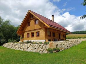 a large wooden house with a stone wall at Roubenka Skalnička in Adršpach