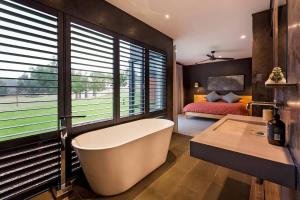 a bathroom with a tub and a bedroom with a bed at Artisan Gunyulgup - Luxe Lakeside Wellness Hideaway in Yallingup