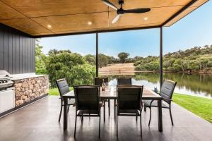 a dining room with a table and chairs and a lake at Artisan Koorabin - Lakeside Luxe Retreat next to Spa in Yallingup