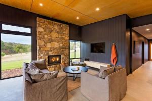 a living room with two couches and a stone fireplace at Artisan Koorabin - Lakeside Luxe Retreat next to Spa in Yallingup