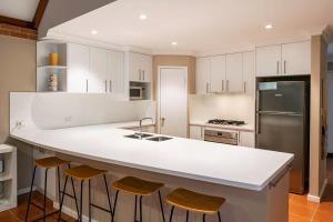 a kitchen with a large white counter and stools at Clearwater - Cosy Comforts Steps from the Beach in Dunsborough