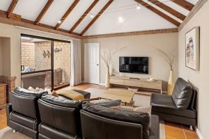 a living room with leather furniture and a flat screen tv at Clearwater - Cosy Comforts Steps from the Beach in Dunsborough